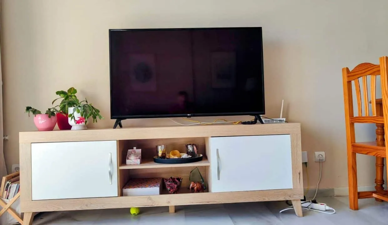 Coin salon : meuble TV en bois clair et chaise en bois – appartement à louer, Las Terrazas de Bel Air, Estepona