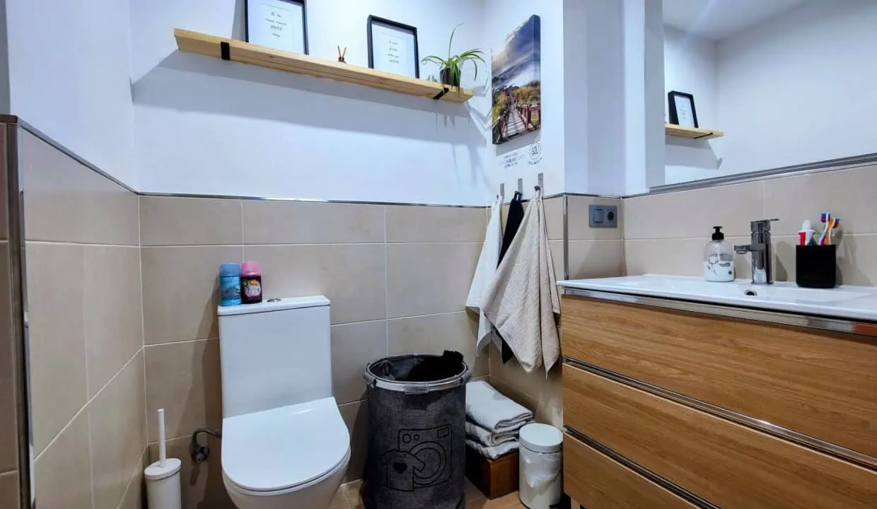 Salle de bain avec WC, meuble vasque en bois et carrelage beige – appartement à louer, Las Terrazas de Bel Air, Estepona