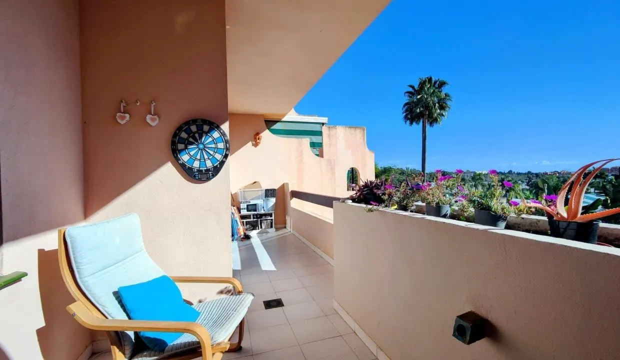 Terrasse avec fauteuil à coussin bleu, cible de fléchettes et fleurs – appartement à louer, Las Terrazas de Bel Air, Estepona