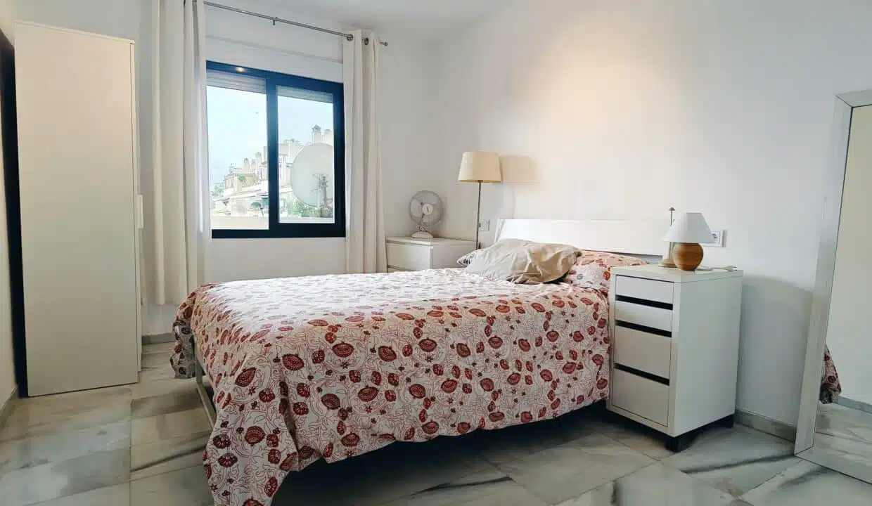 Chambre double au couvre-lit à fleurs rouges et grand miroir – appartement à louer, Las Terrazas de Bel Air, Estepona