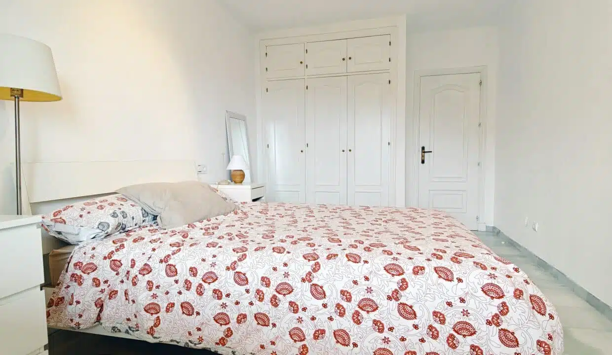 Chambre avec lit double, couette à fleurs rouges et armoire blanche – appartement à louer, Las Terrazas de Bel Air, Estepona