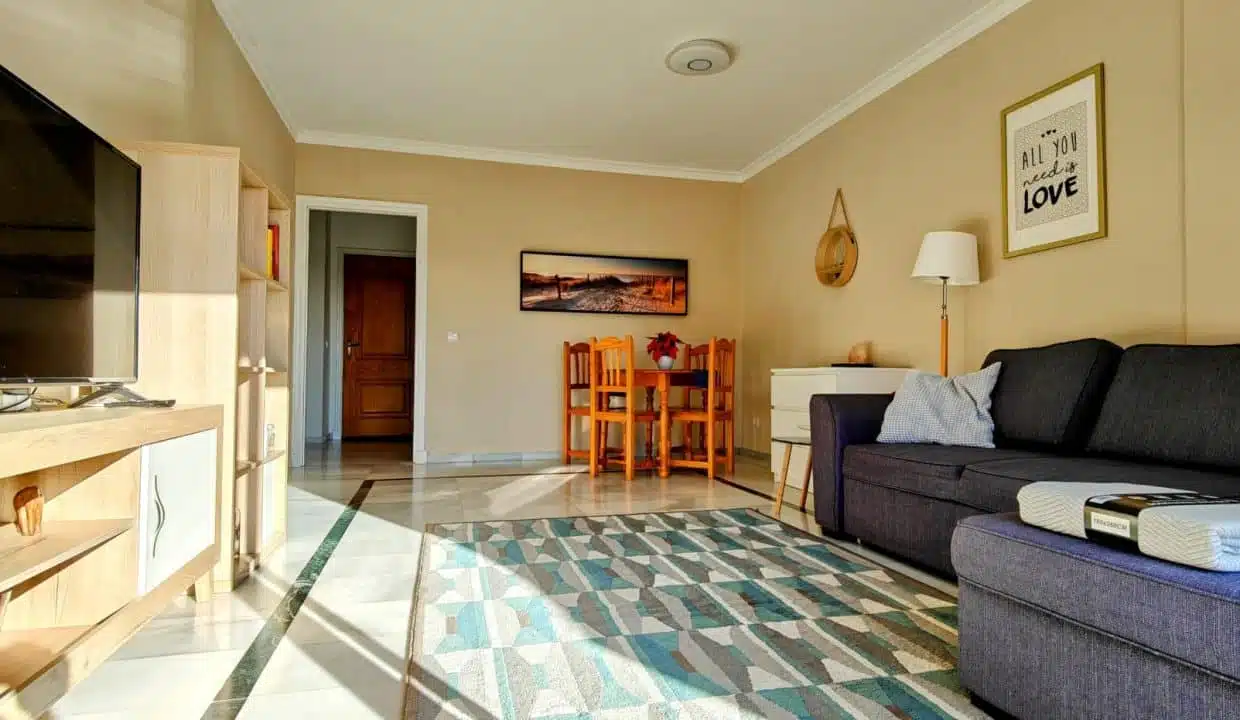 Séjour avec canapé gris, meuble TV clair et chaises orange – appartement à louer, Las Terrazas de Bel Air, Estepona