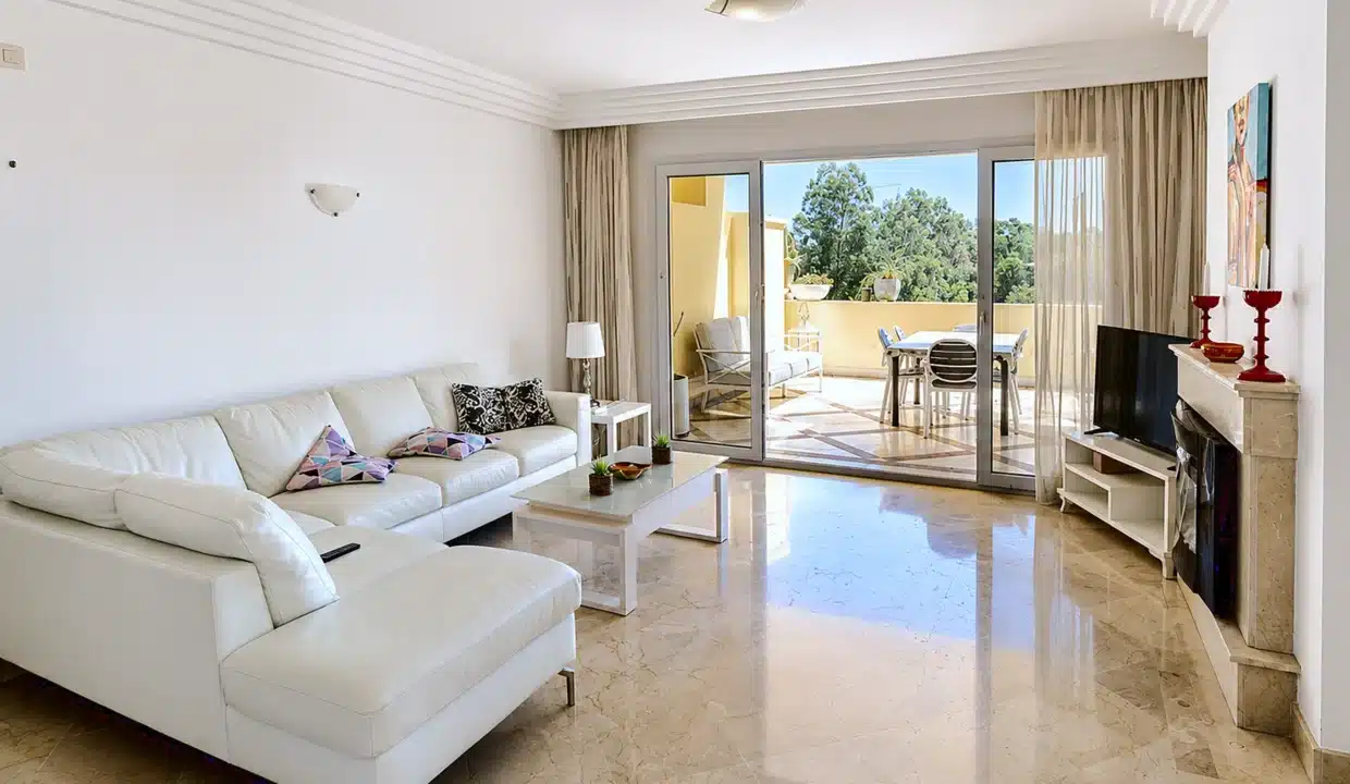 Salón con sofá rinconera blanco, chimenea – apartamento en alquiler, Majestic Hills, Casares (ref. AL014)