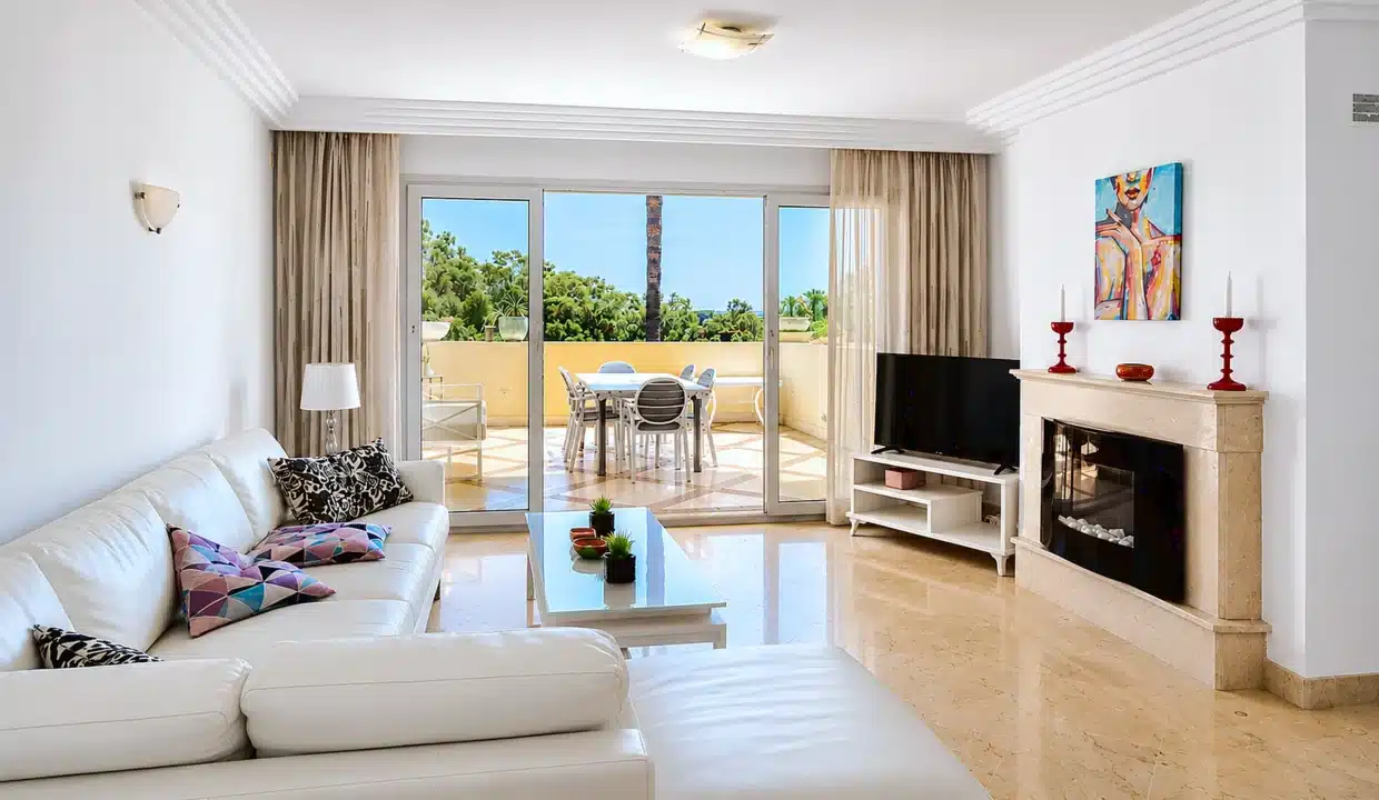 Salón con sofá rinconero blanco, chimenea – apartamento en alquiler, Majestic Hills, Casares (ref. AL014)