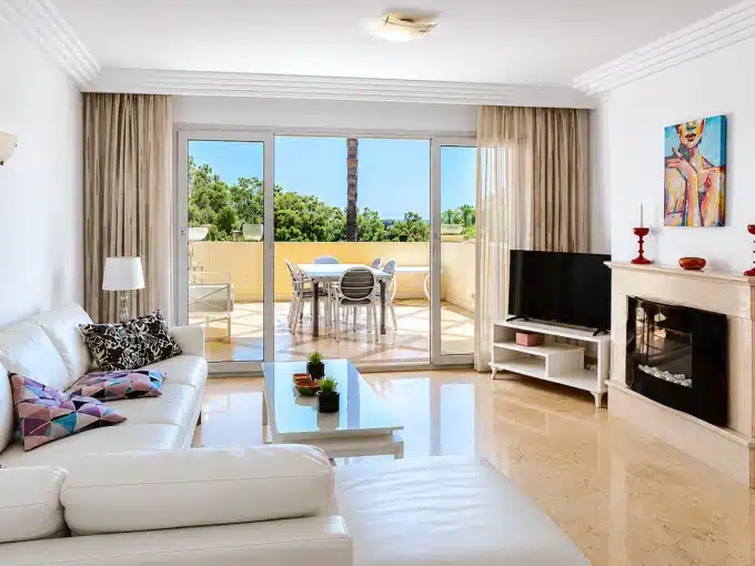 Living room with white corner sofa, fireplace – apartment for rent, Majestic Hills, Casares (ref. AL014)