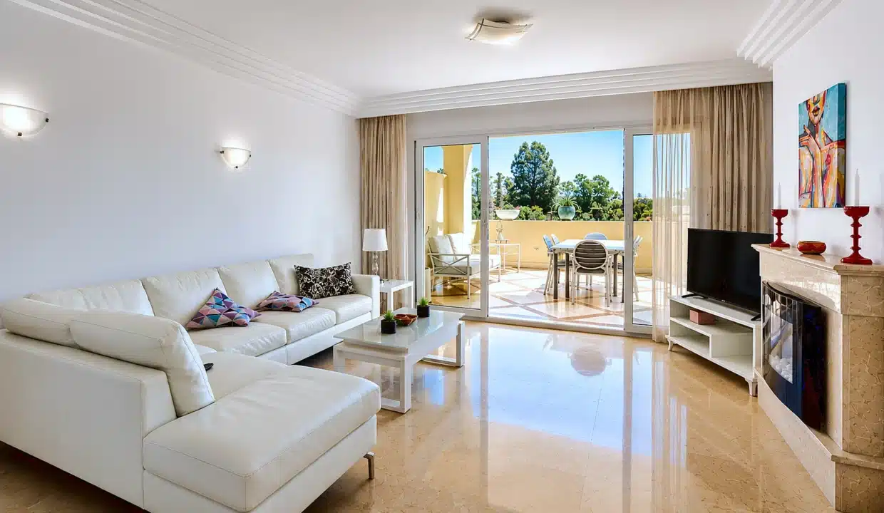 Salón con sofá esquinero blanco, chimenea – apartamento en alquiler, Majestic Hills, Casares (ref. AL014)