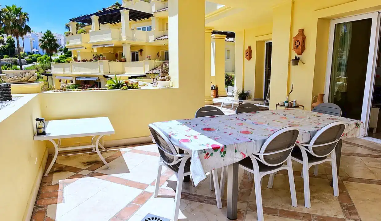 Terraza soleada de paredes amarillas con mesa, sillas – apartamento en alquiler, Majestic Hills, Casares (ref. AL014)