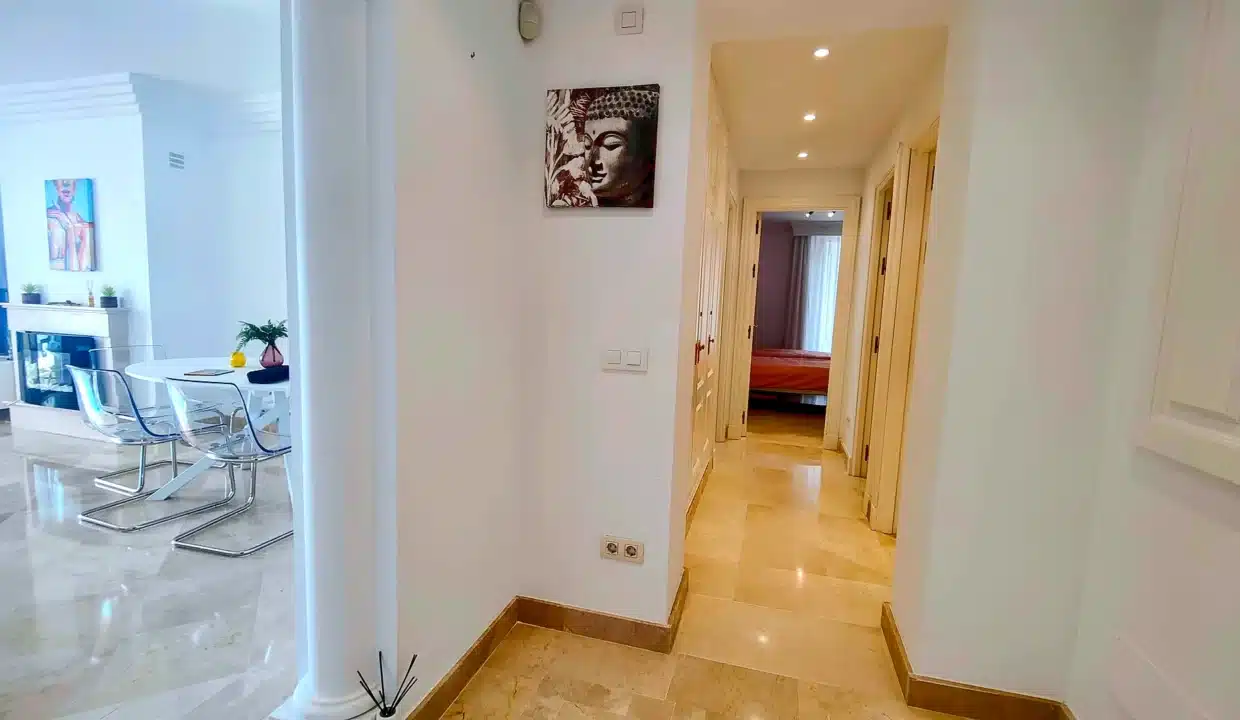 Pasillo luminoso con cuadro de Buda y comedor a la izquierda – apartamento en alquiler, Majestic Hills, Casares (ref. AL014)