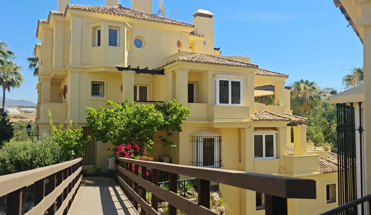 Edificio amarillo con tejados de teja, pasarela de madera – apartamento en alquiler, Majestic Hills, Casares (ref. AL014)