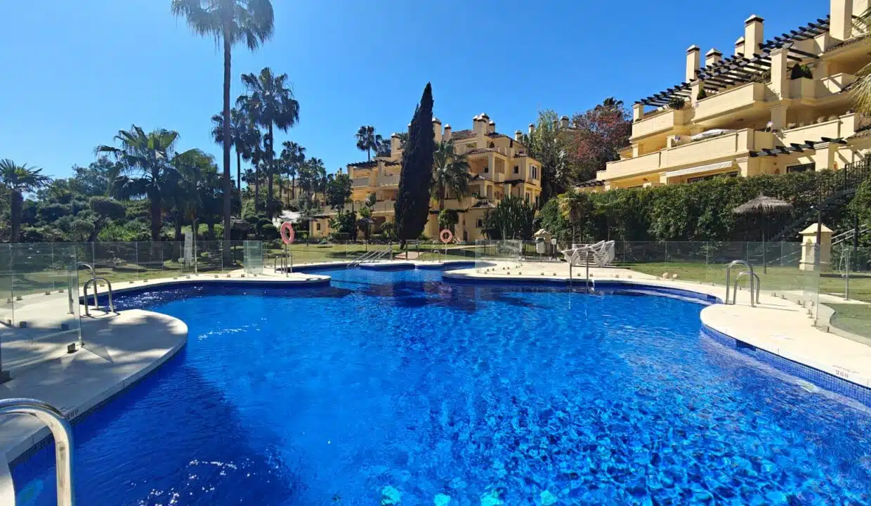 Gran piscina de la residencia rodeada de edificios ocre – apartamento en alquiler, Majestic Hills, Casares (ref. SUM014)