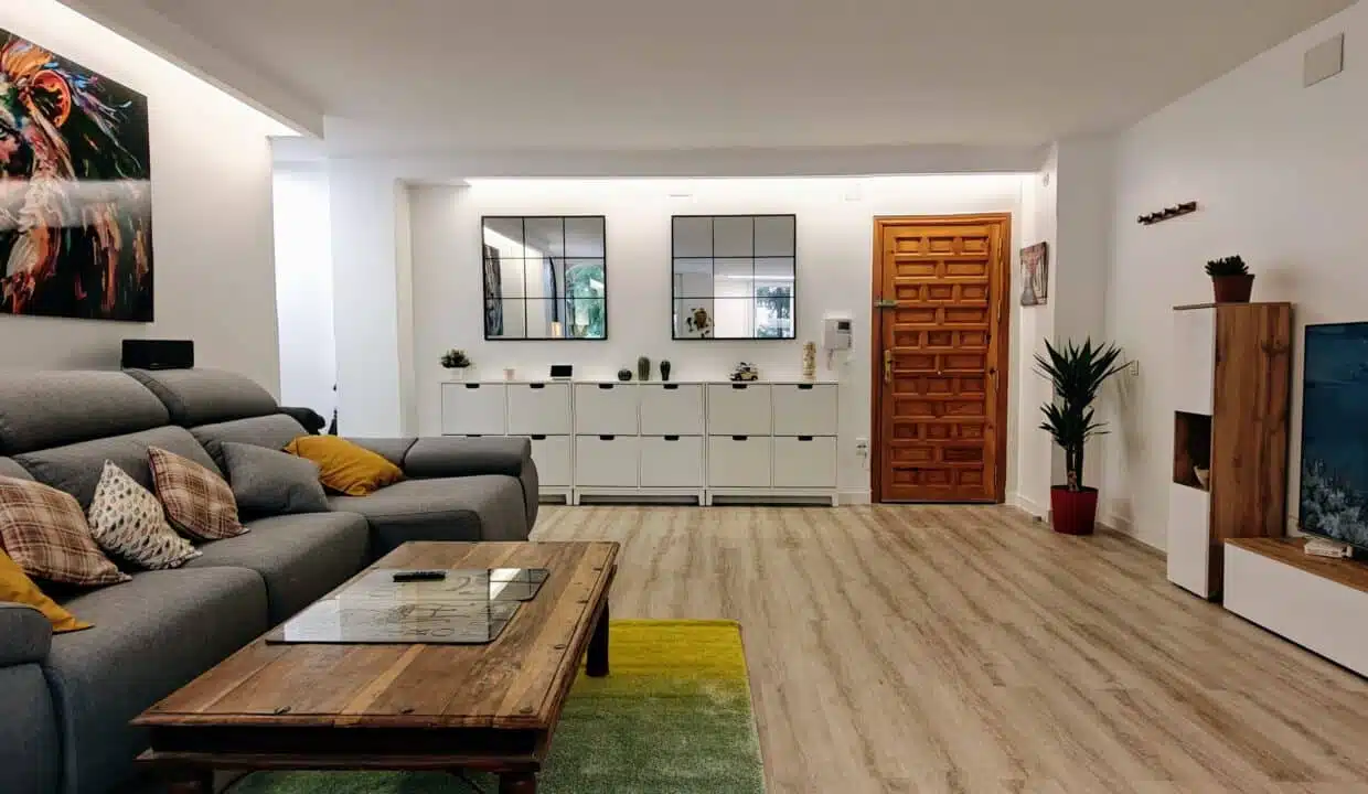 Living room with grey sectional sofa, yellow cushions and a large lion painting – apartment for rent, Estepona town centre