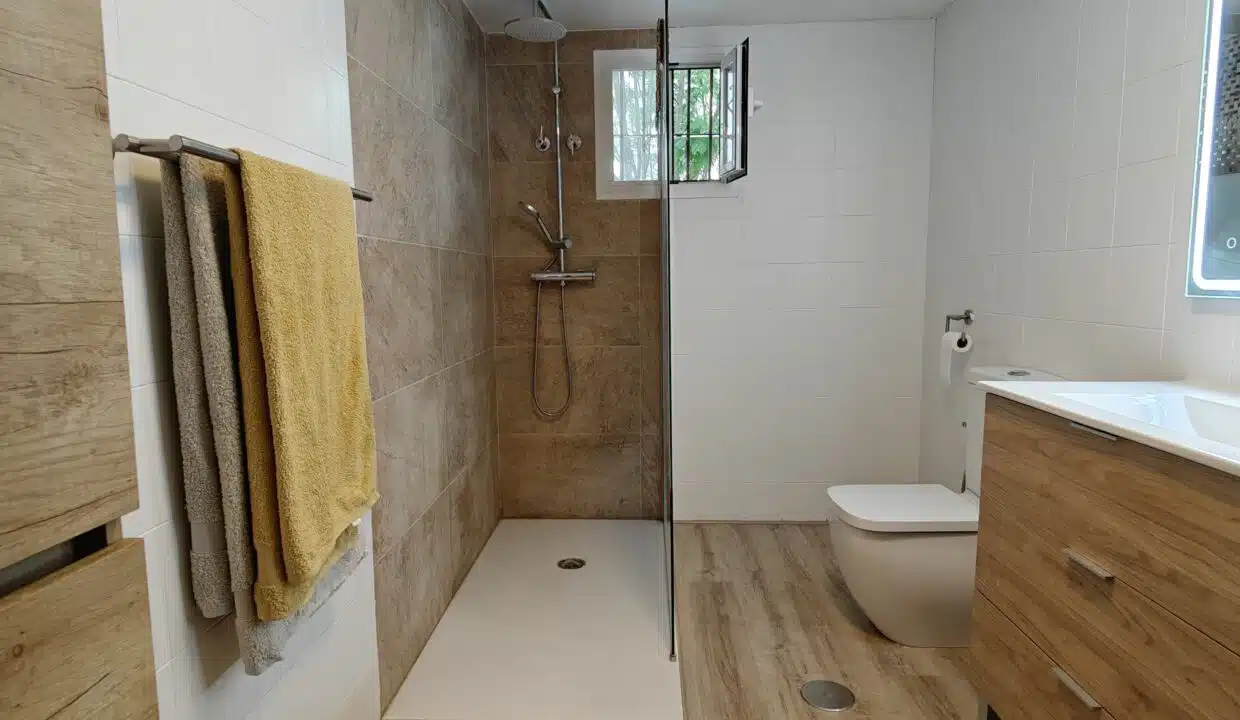 Bathroom with walk-in shower, wooden vanity and illuminated mirror – apartment for rent, Estepona town centre