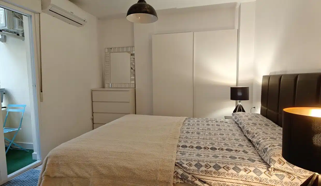 Double bedroom with dark headboard, white wardrobe and glass door to the balcony – apartment for rent, Estepona town centre