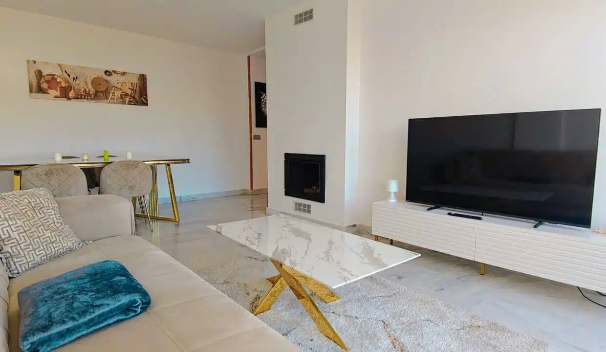 Salon avec canapé beige, table basse effet marbre et cheminée – appartement à louer, Parque Botanico, Benahavís (réf. AL035)