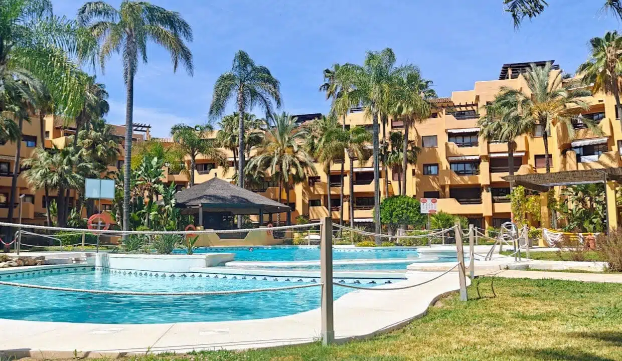 Residence pool with palm trees and ochre buildings – apartment for rent, Terrazas de Costalita, Estepona (ref. AL037)
