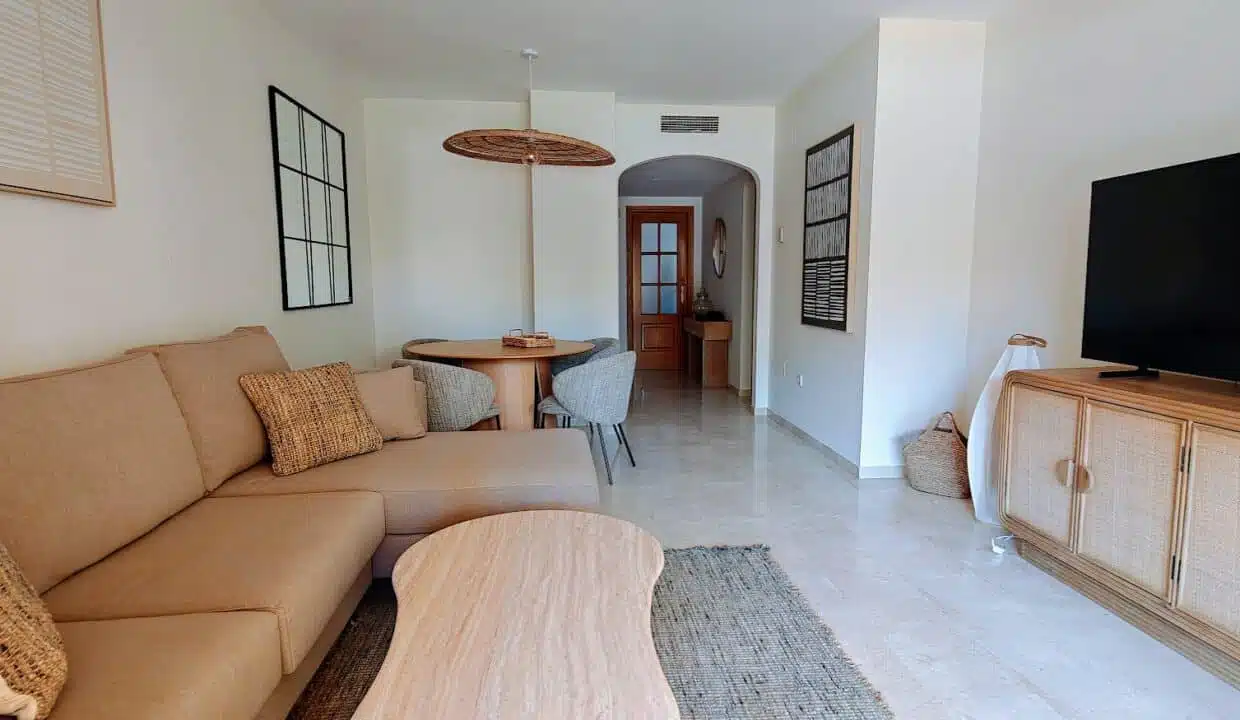 Living room with beige corner sofa and rattan TV unit – apartment for rent, Terrazas de Costalita, Estepona (ref. AL037)