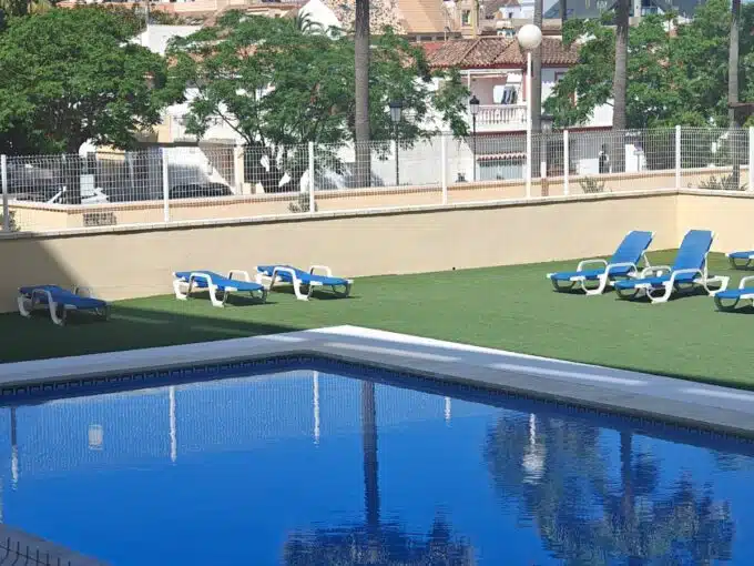 Communal pool and blue sun loungers lined up on the lawn – apartment for rent, Sabinillas, Manilva (ref. AL020)
