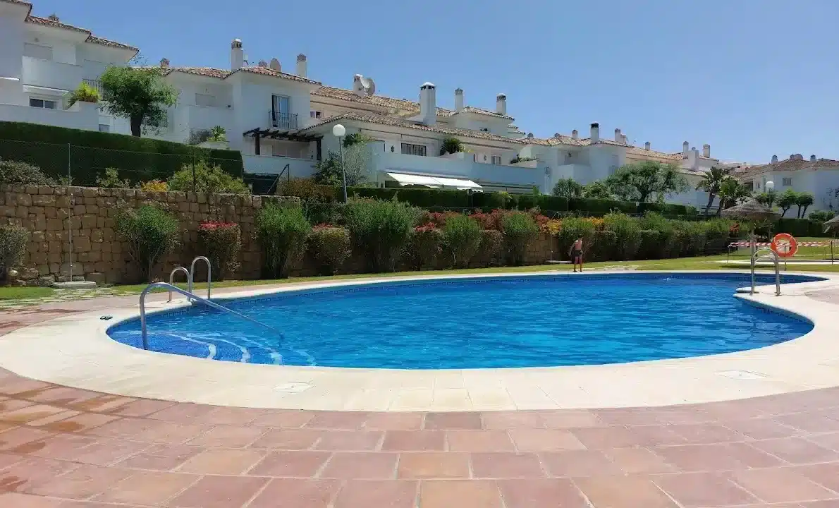 Piscina de formas curvas frente a casas blancas y un seto – apartamento en alquiler, Casares Real, Casares (ref. SUM003)