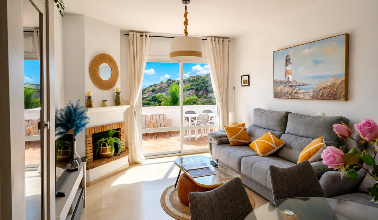 Salon avec canapé gris à coussins moutarde, cheminée en briques – appartement à louer, Casares Real, Casares (réf. SUM003)