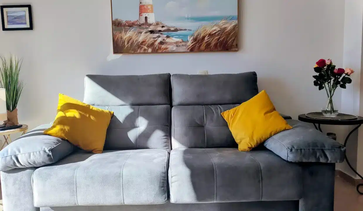 Salon avec canapé gris, coussins jaunes et tableau de phare au mur – appartement à louer, Casares Real, Casares (réf. SUM003)