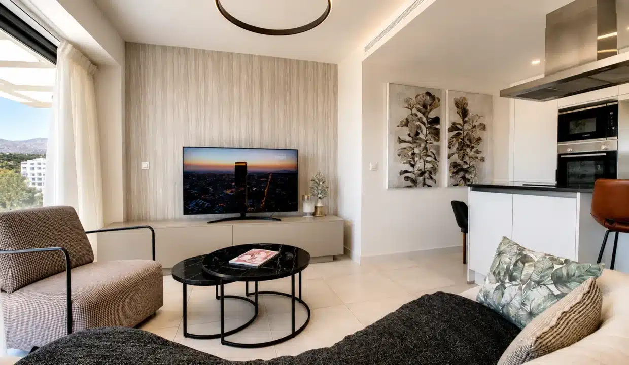 Salon avec TV, tables basses noires rondes et cuisine ouverte au fond – appartement à louer, Oasis 325, Estepona (réf. AL038)