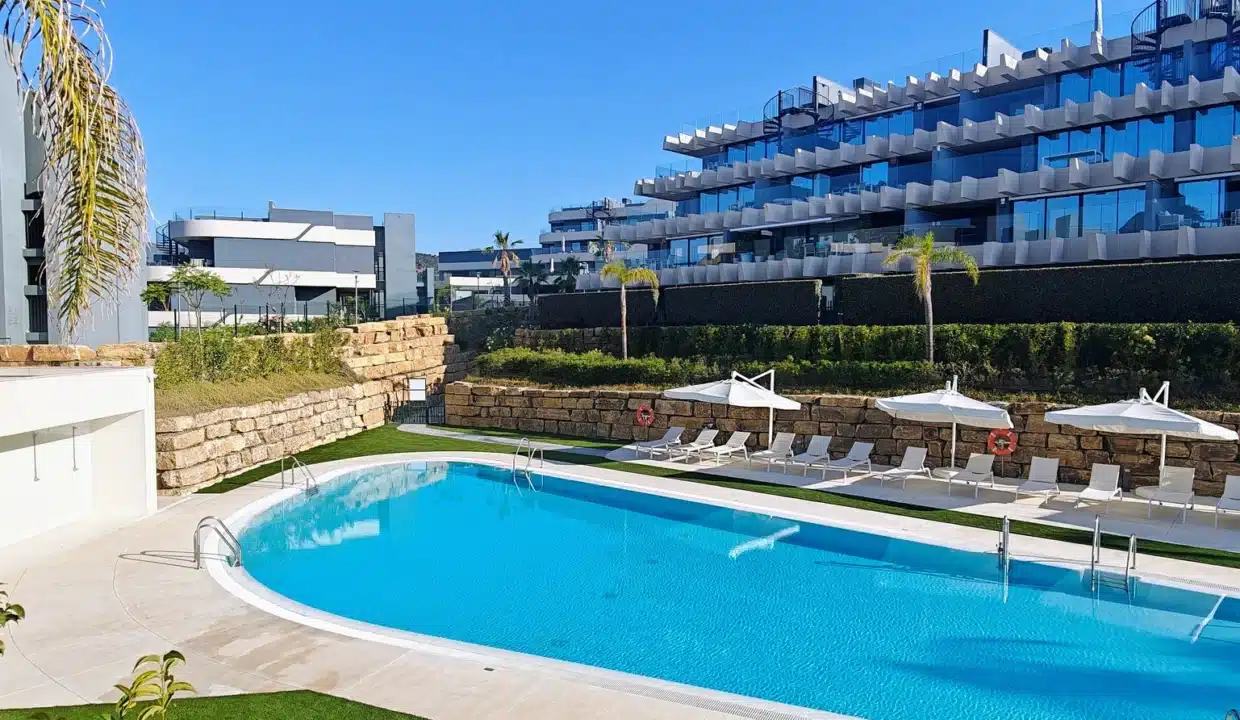 Piscine commune, transats et parasols blancs devant la résidence – appartement à louer, Oasis 325, Estepona (réf. AL038)