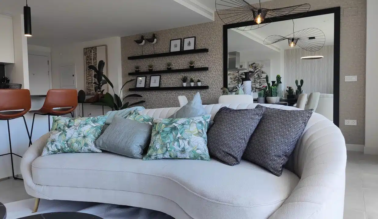 Canapé crème arrondi à coussins tropicaux, tabourets en cuir – appartement à louer, Oasis 325, Estepona (réf. SUM038)