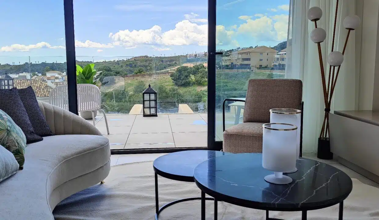 Salon aux deux tables basses rondes et baie vitrée sur les collines – appartement à louer, Oasis 325, Estepona (réf. SUM038)