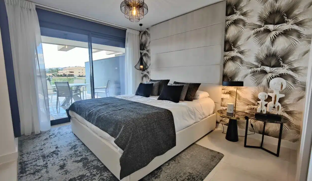 Chambre double avec papier peint à palmes et porte vers la terrasse – appartement à louer, Oasis 325, Estepona (réf. SUM038)