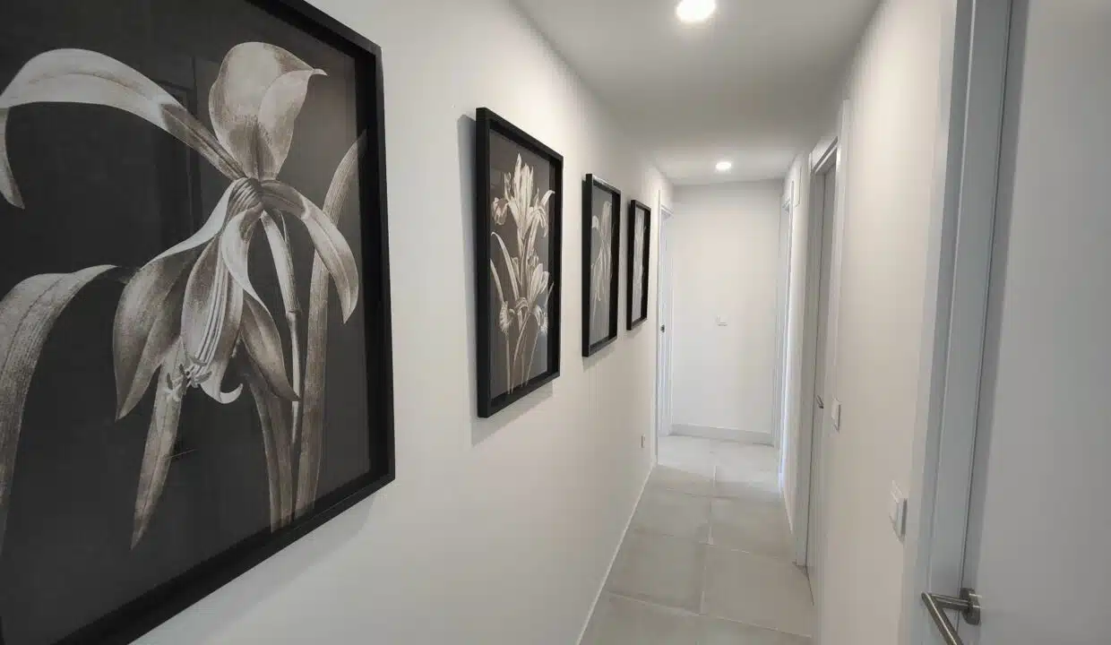 Couloir aux cadres noirs de fleurs blanches et carrelage gris clair – appartement à louer, Oasis 325, Estepona (réf. SUM038)