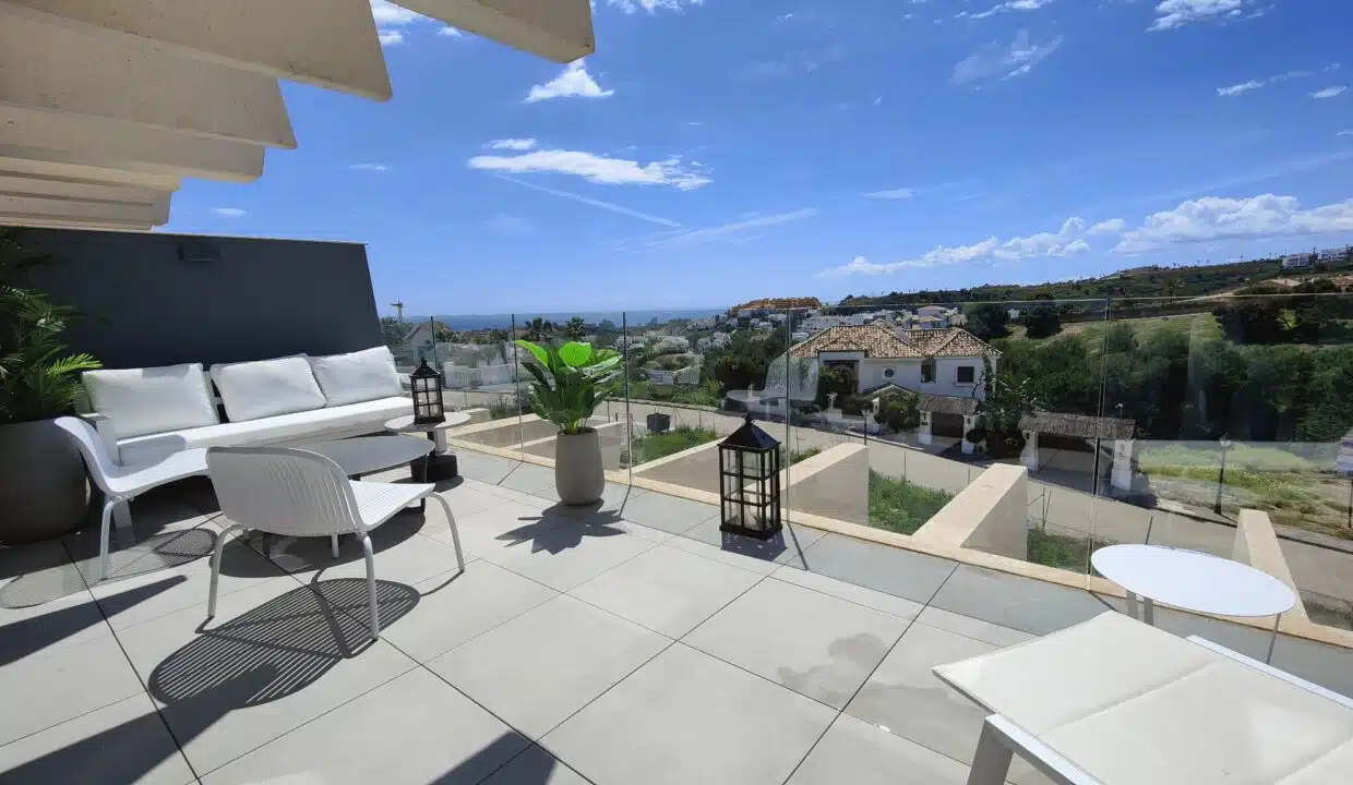 Terrasse vitrée avec canapé blanc, lanternes et vue sur les collines – appartement à louer, Oasis 325, Estepona (réf. SUM038)