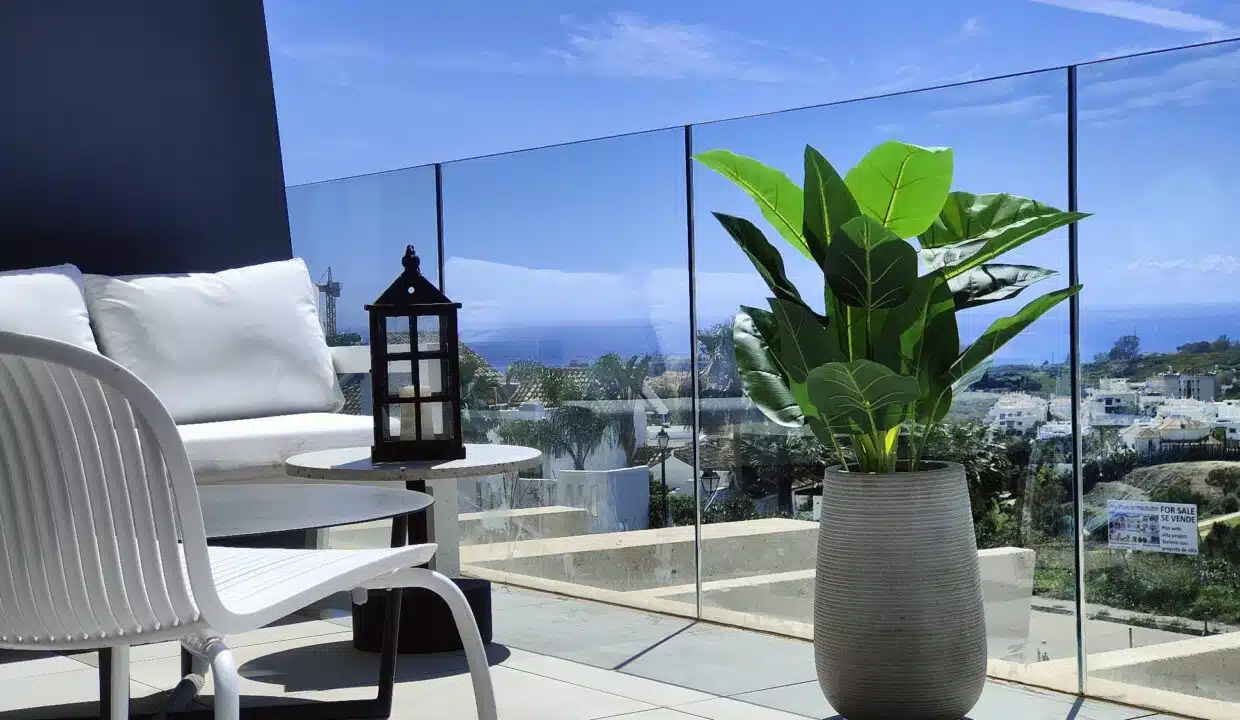 Terrasse avec garde-corps en verre, plante verte et mer au loin – appartement à louer, Oasis 325, Estepona (réf. SUM038)