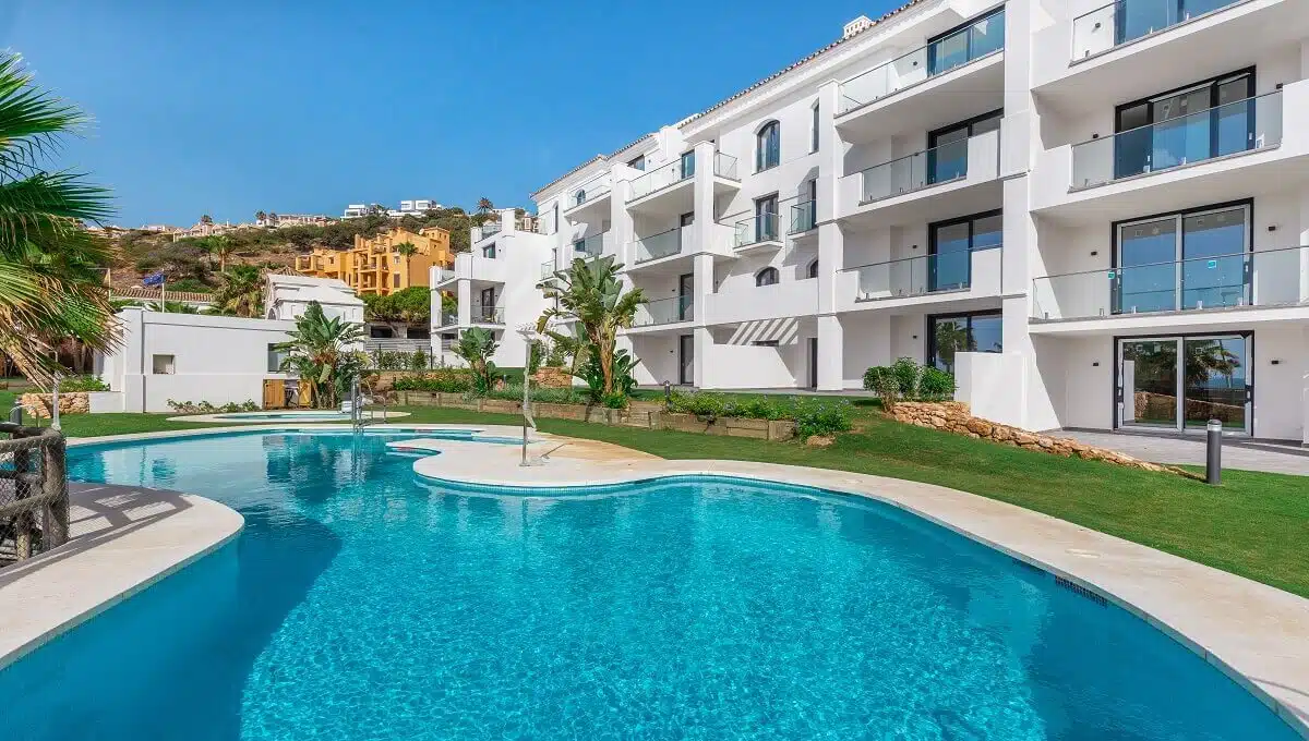 Piscina de formas libres frente a un edificio blanco – apartamento en alquiler, Paloma, Manilva (ref. AL054)