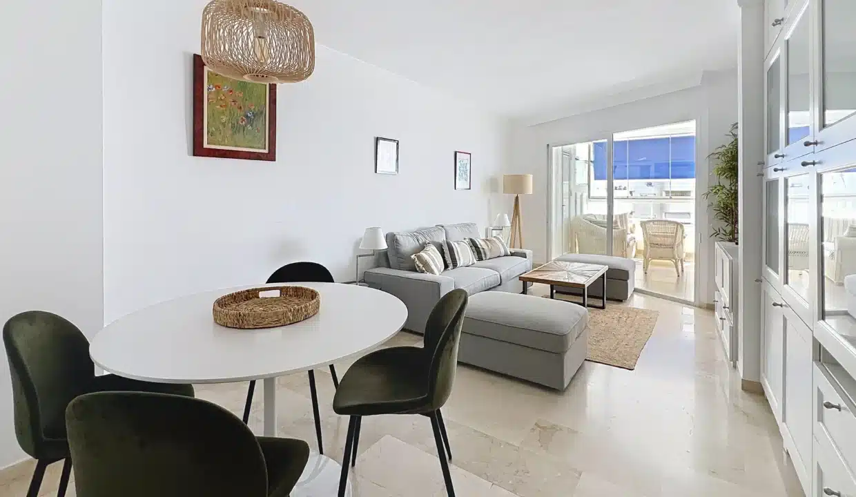 Salon-salle à manger clair avec table ronde blanche et chaises vertes – appartement à louer, port d'Estepona (réf. AL051)