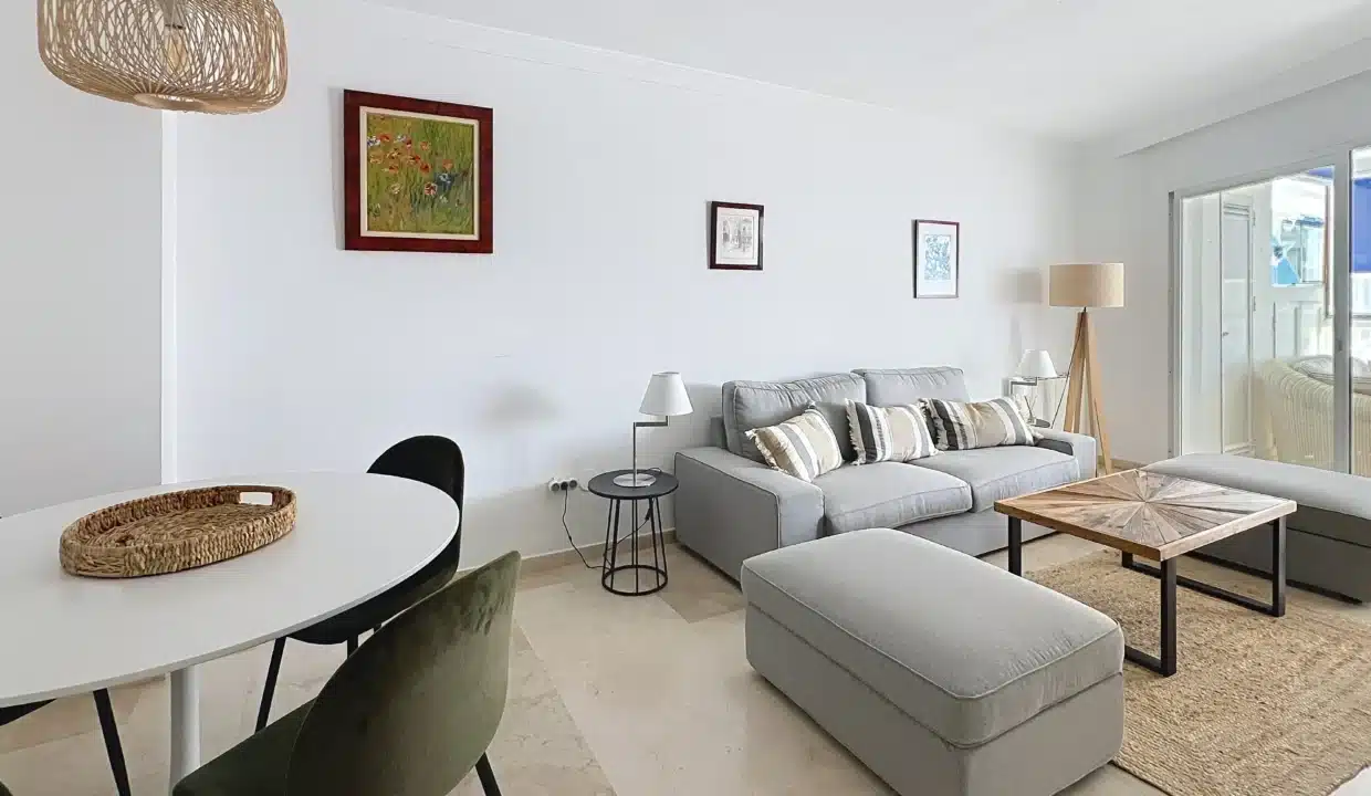 Séjour avec canapé gris, table ronde blanche et chaises en velours vert – appartement à louer, port d'Estepona (réf. AL051)
