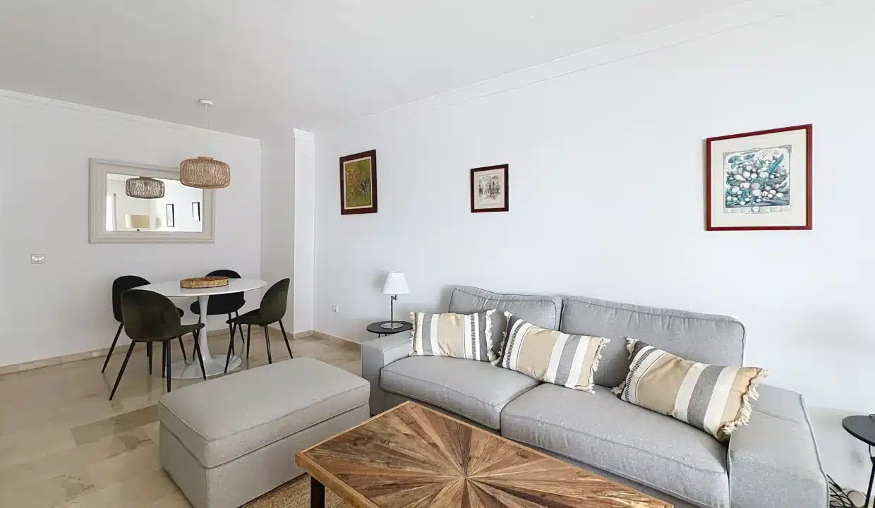 Salon avec canapé gris, table basse en bois en étoile et coin repas rond – appartement à louer, port d'Estepona (réf. AL051)