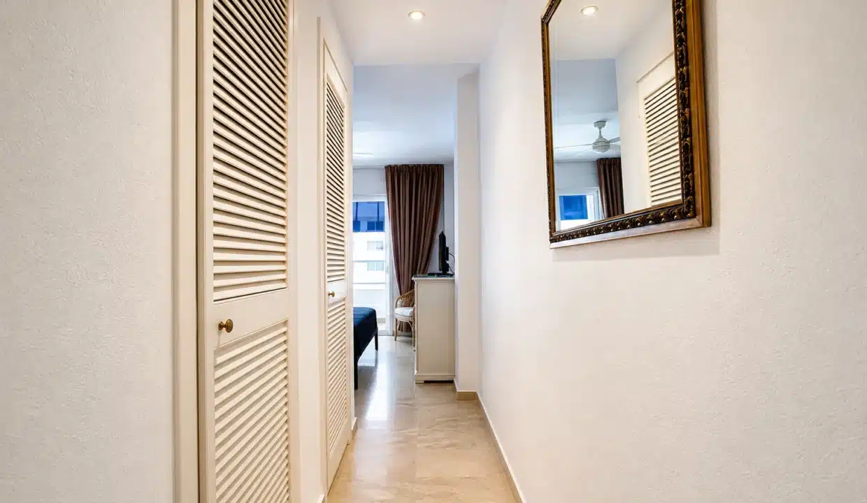 Couloir d'entrée aux portes persiennées blanches et miroir doré – appartement à louer, port d'Estepona (réf. AL051)