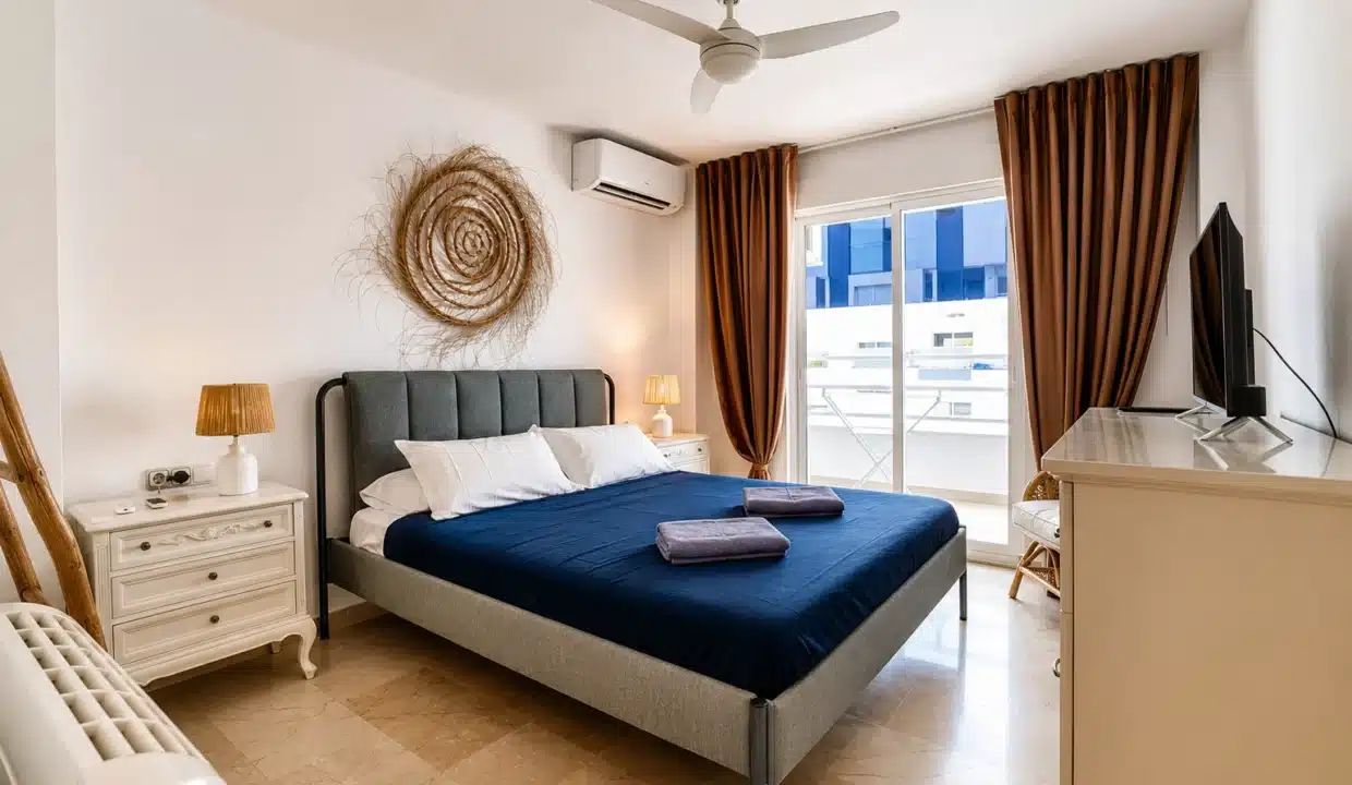 Chambre double au couvre-lit bleu marine, tête de lit grise – appartement à louer, port d'Estepona (réf. AL051)