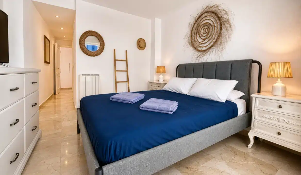Chambre au linge bleu marine, tête de lit grise et commode blanche – appartement à louer, port d'Estepona (réf. AL051)