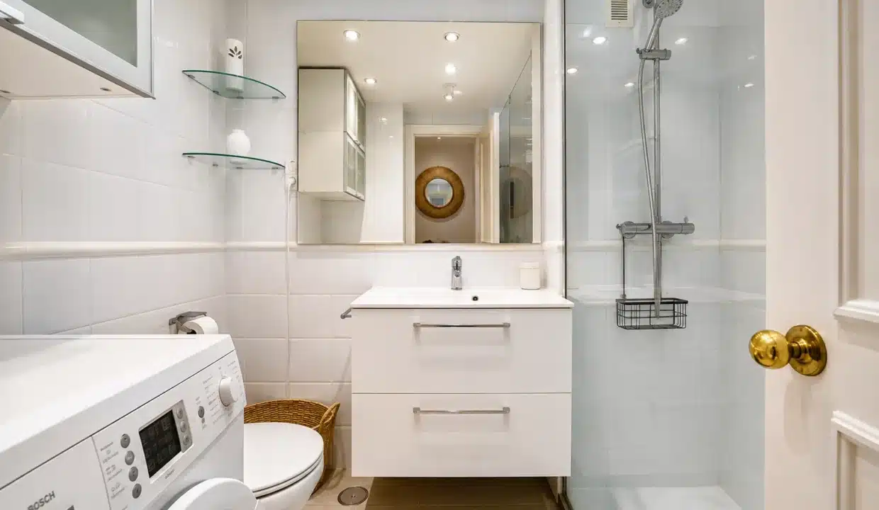 Salle de bain blanche avec douche, meuble vasque suspendu et lave-linge – appartement à louer, port d'Estepona (réf. AL051)